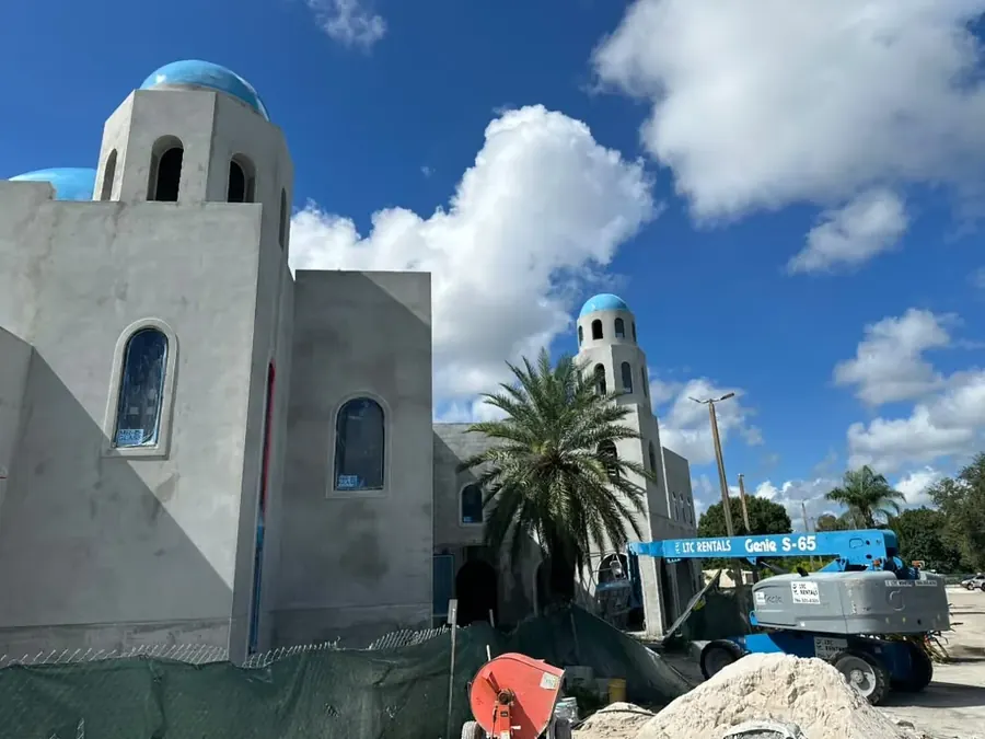 Two corner towers and their blue domes from inside the site, with a boom lift and a concrete mixer working below